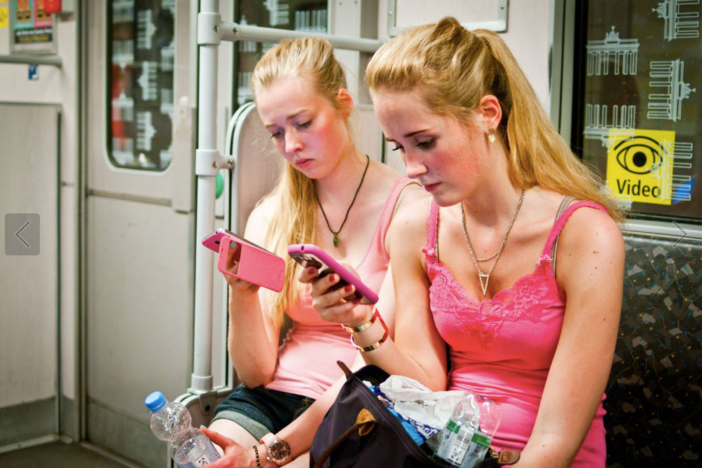 Two girls at a subway with their phones